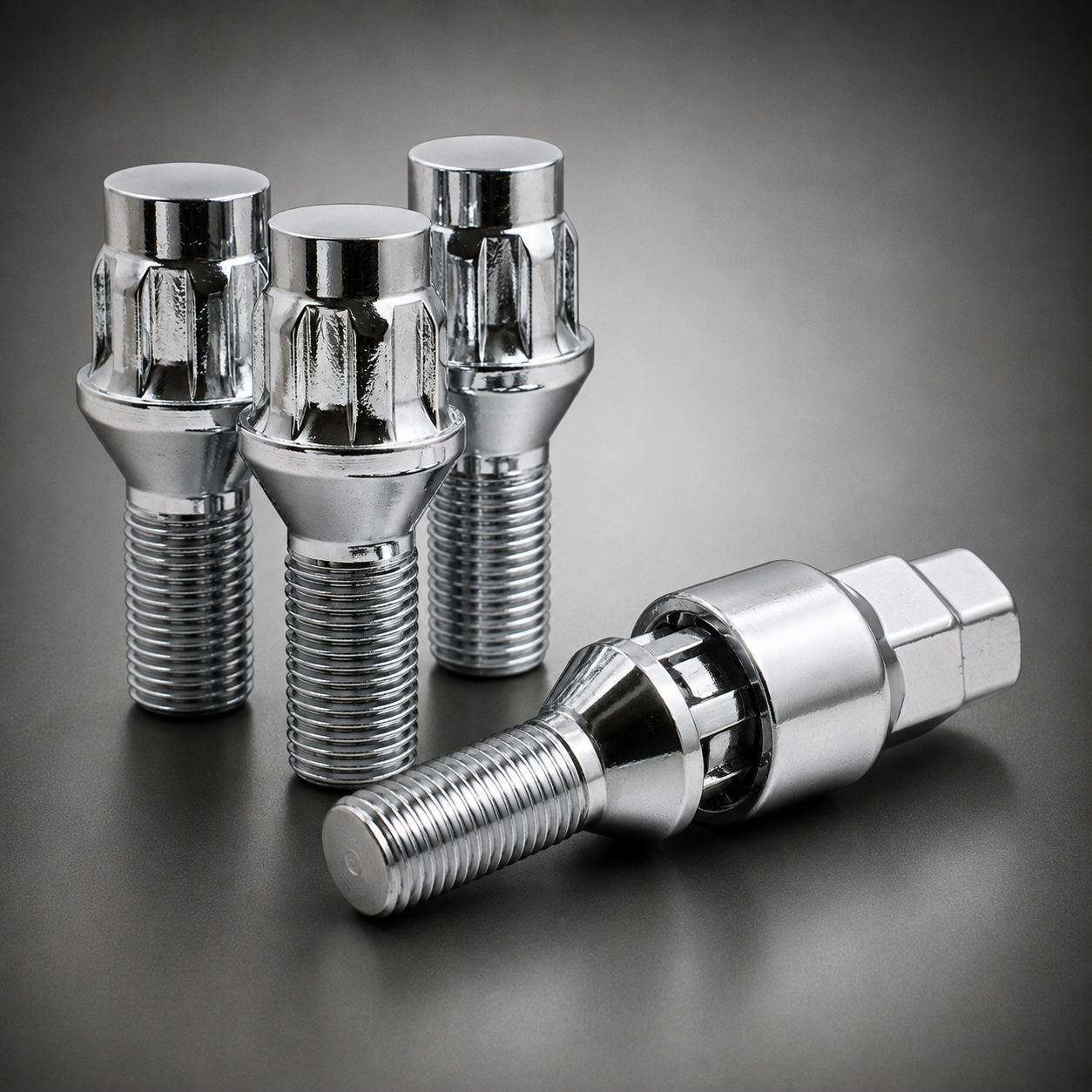 Four shiny chrome metal locking wheel lug bolts arranged on a dark gray studio background, with three standing upright and one lying on its side nested in the lock key socket